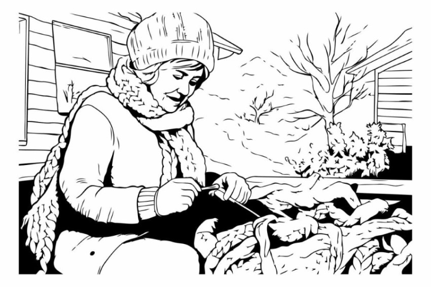 A woman in winter clothes is sitting at the table in the garden.